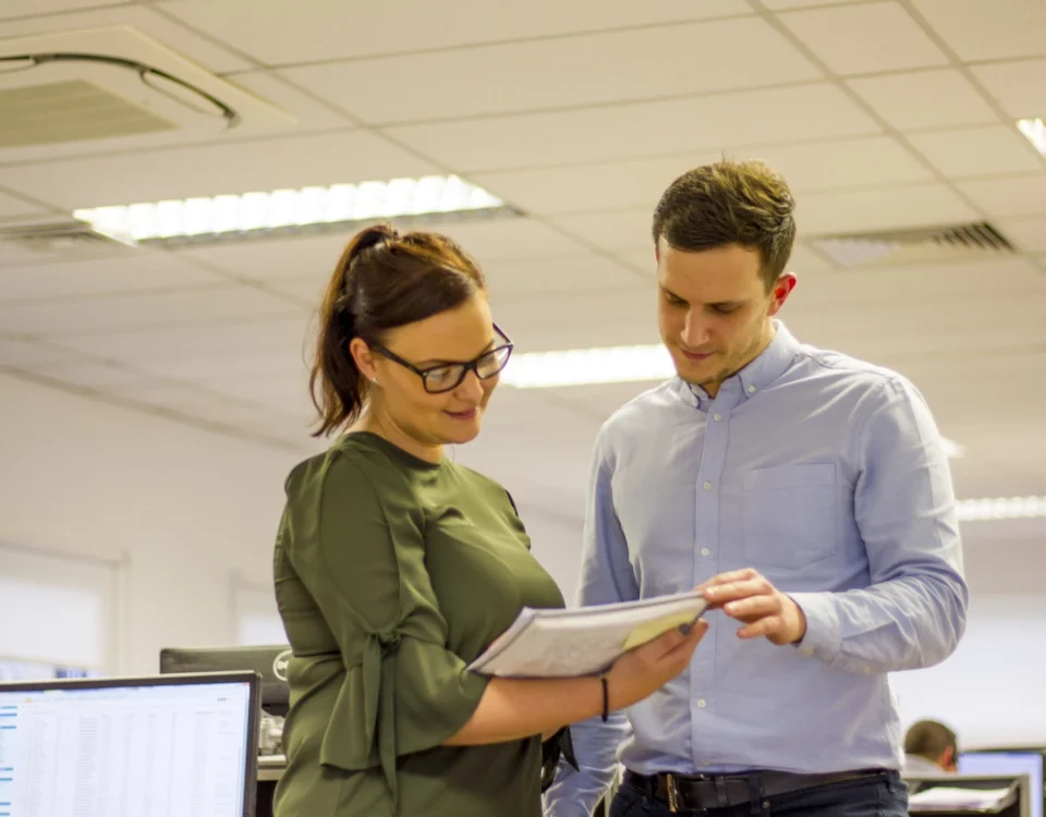 Two young professionals in an office, reviewing a document together